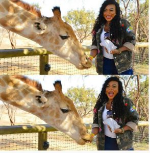 Daniella Okeke Poses With a Giraffe.